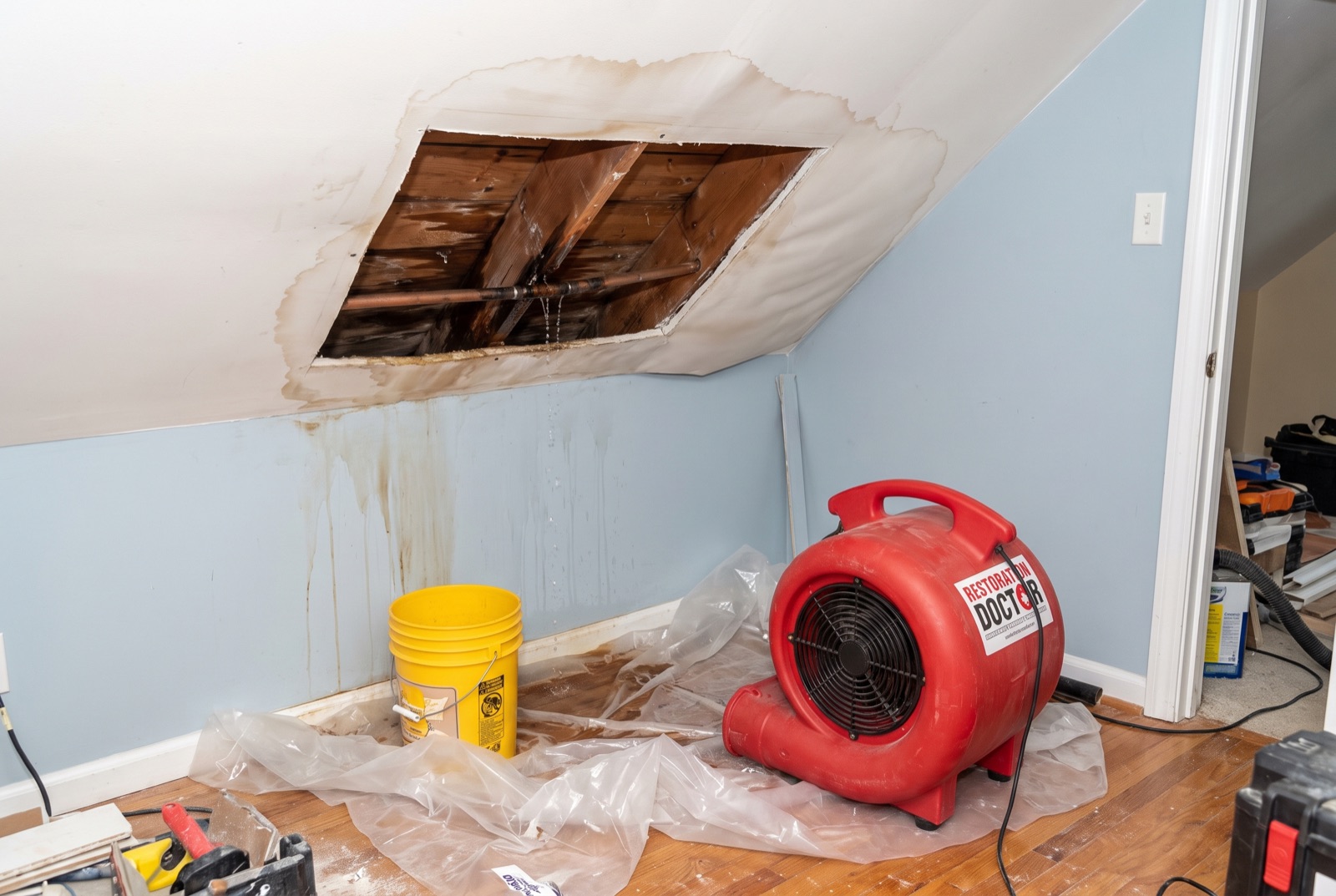 Opened ceiling exposing a burst supply pipe with drying in progress — illustrating: how do I keep my pipes from freezing