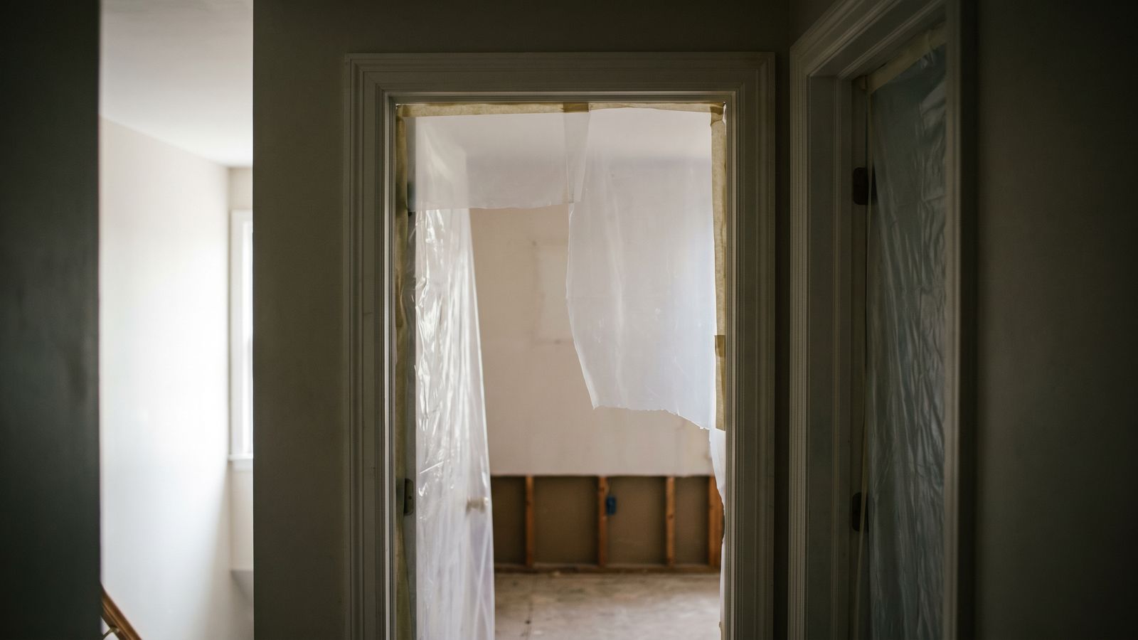 Sheeting across a doorway to a stripped room Plastic sheeting hung across a hallway doorway into a stripped room with a flood cut, marking off a structural drying zone
