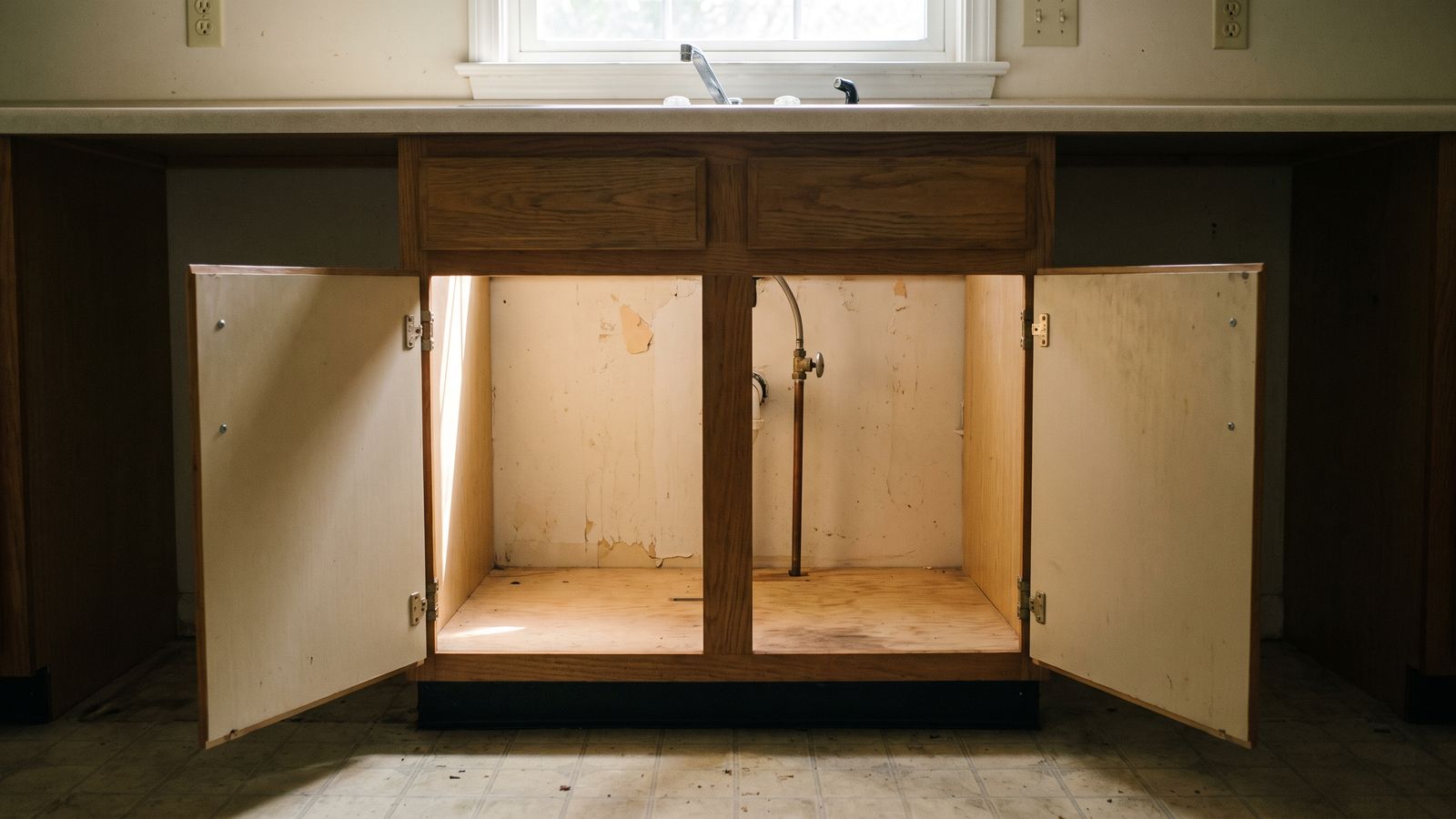 Sink cabinet doors open to the supply riser Kitchen sink base cabinet with both doors open to warm the copper supply riser and prevent frozen pipes