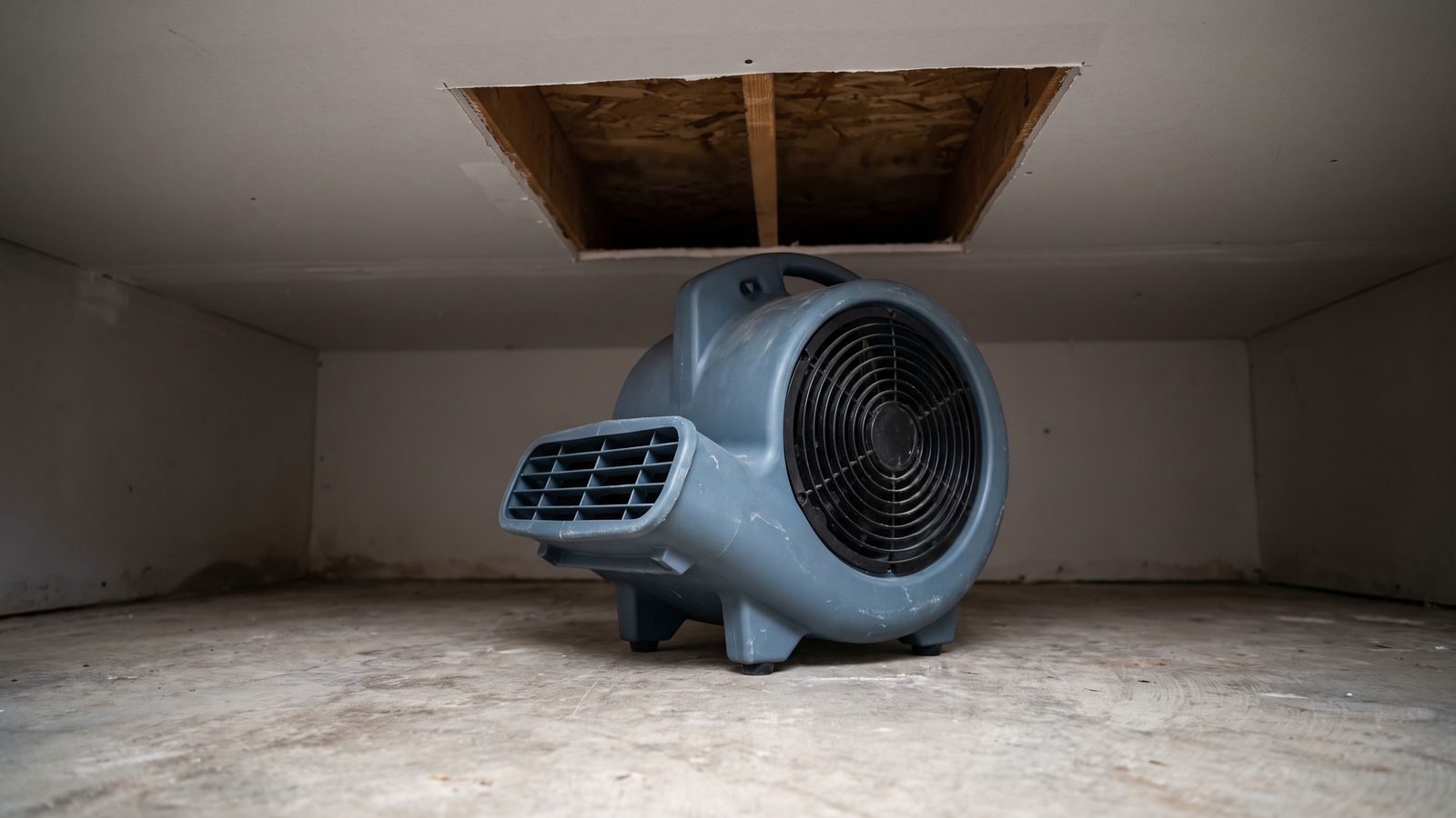 Centrifugal air mover on a slab below an opened ceiling cavity, equipment that shortens how long water damage takes to dry