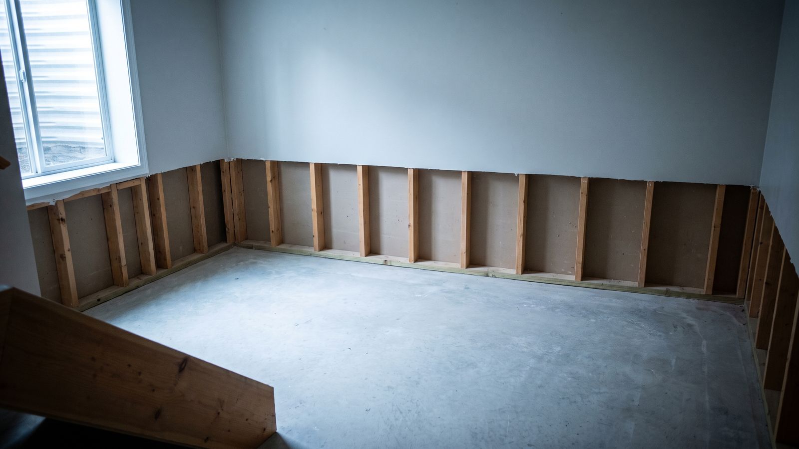 Flood cut exposing bare studs above a basement slab, the scope after water damage