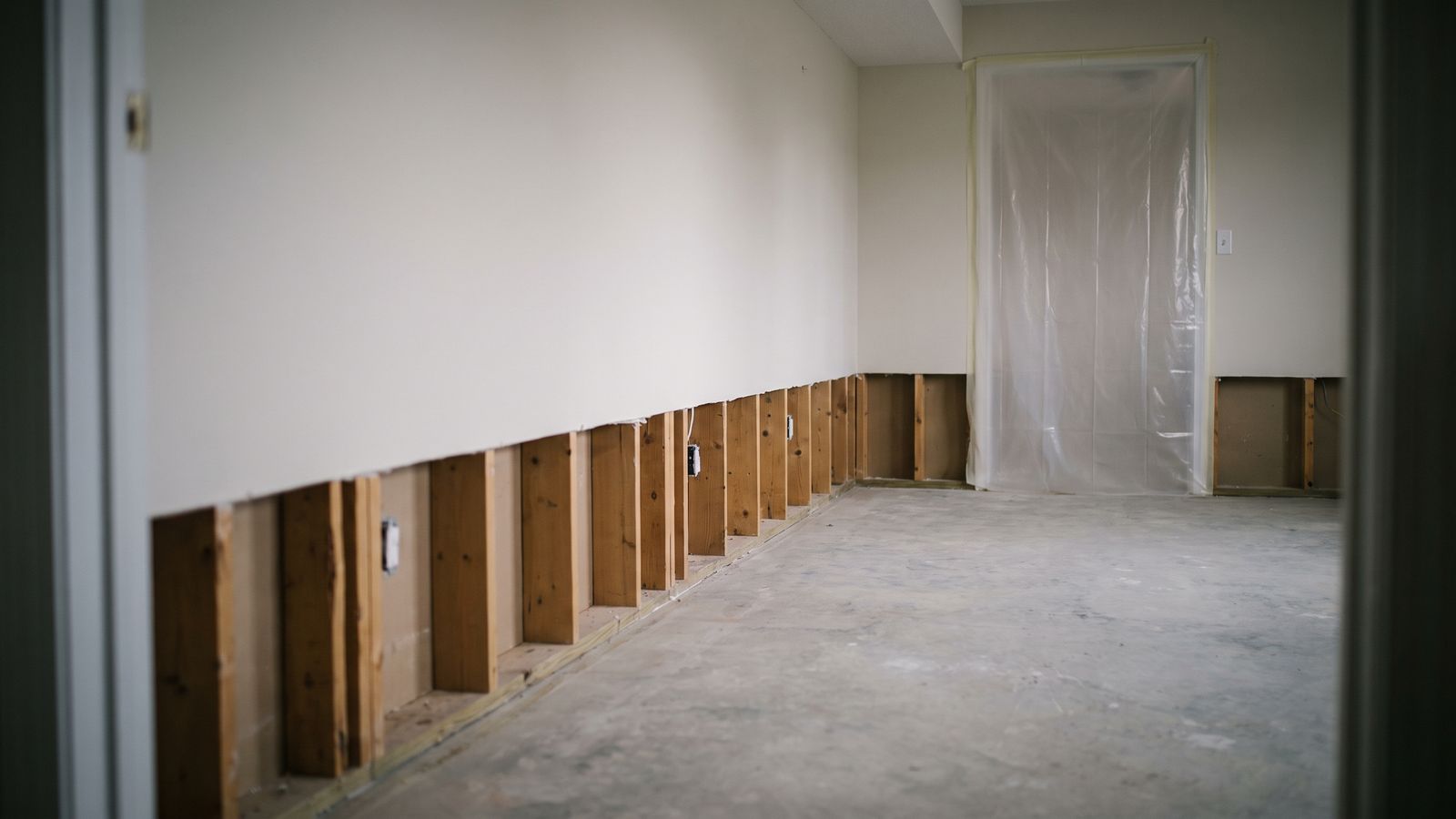 Drywall cut back in a straight line to open studs with a sheeted doorway beyond, how to remove mold from drywall by cutting