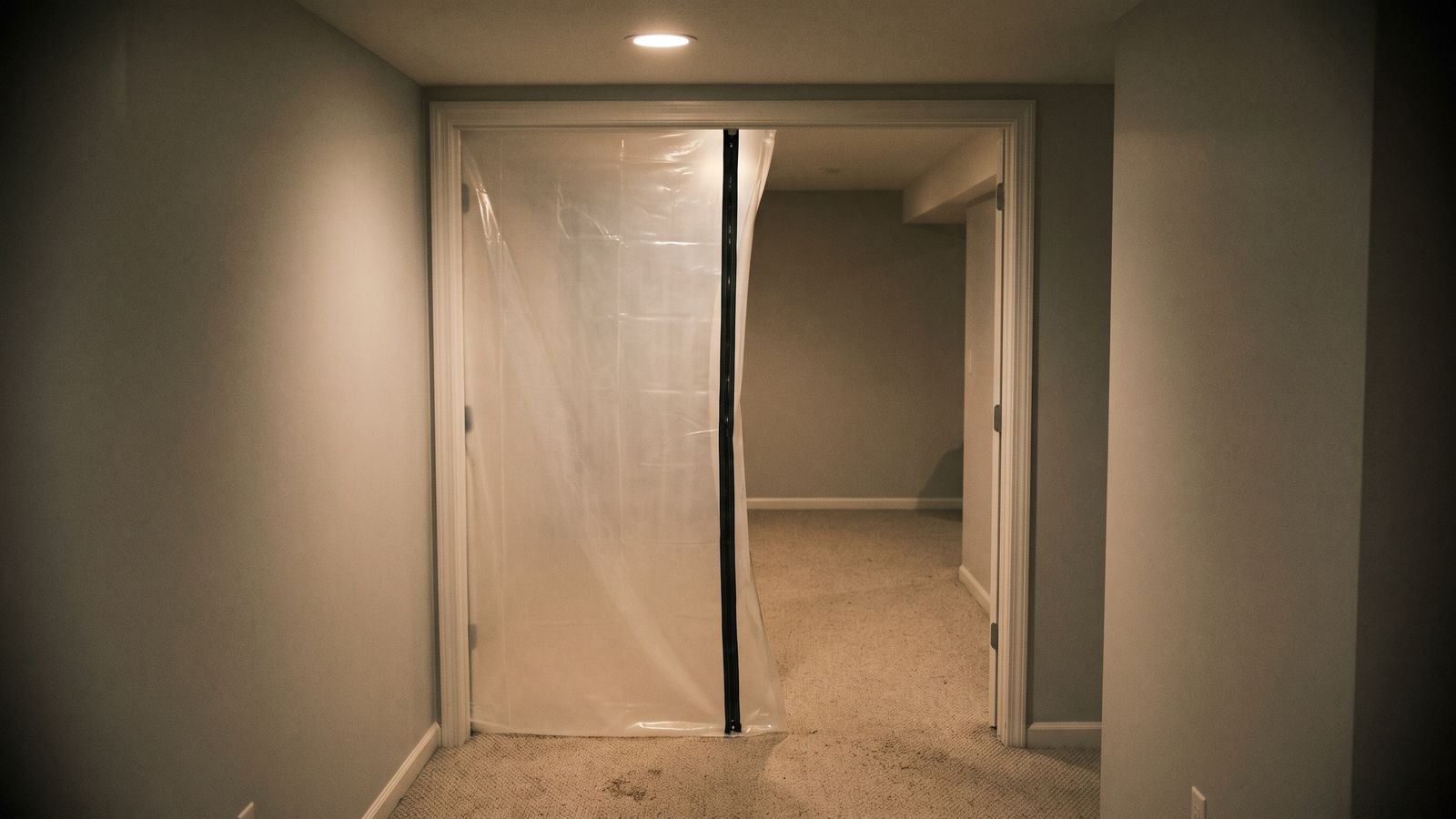 Zippered containment sheeting at a basement doorway Plastic containment sheeting hung across a basement doorway, the barrier used when living in a house with mold