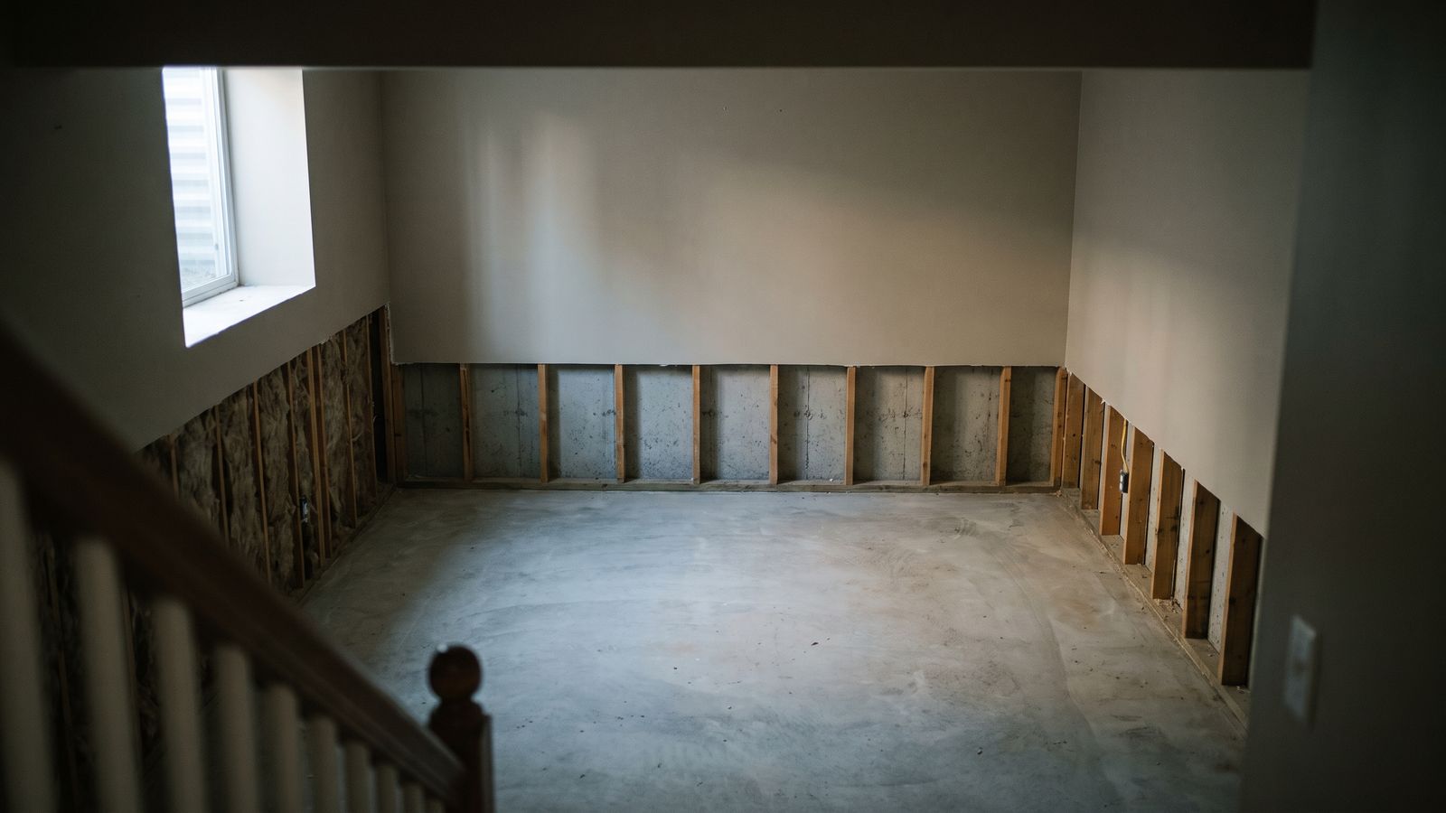 Basement drywall cut back to bare studs Basement drywall cut back to bare studs above a swept slab, the removal step that follows mold exposure symptoms