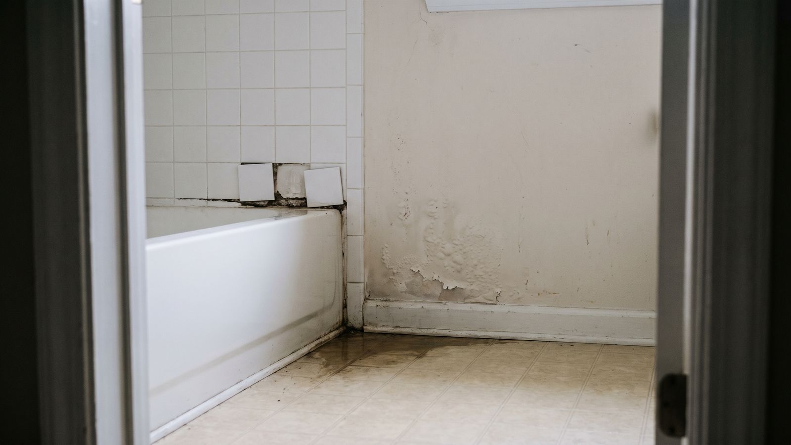 Loose shower tiles and blistered paint by a tub Loose shower wall tiles, a blackened tub seam and blistered paint show classic pipe leak behind shower wall signs