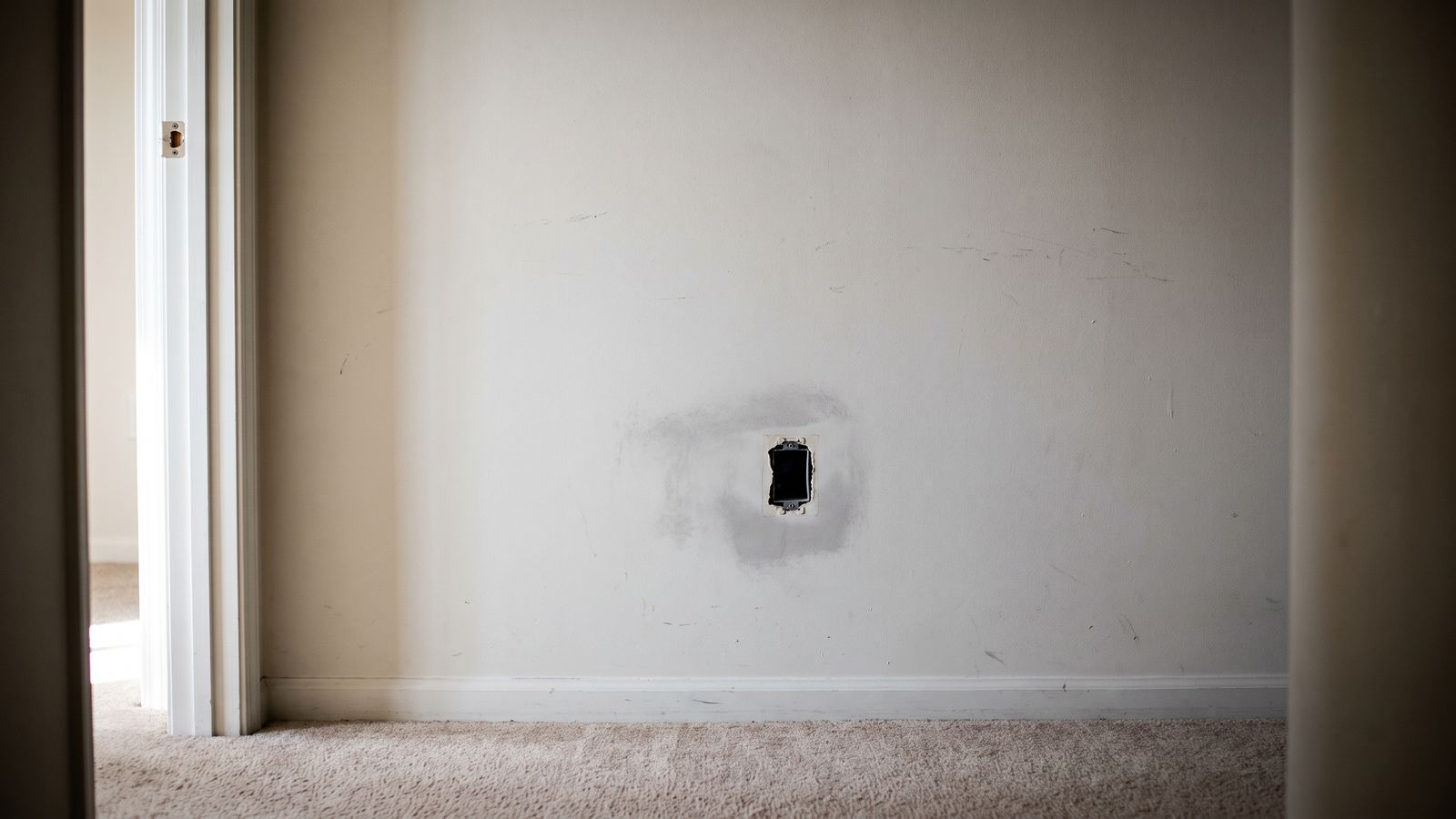 Outlet with its cover plate removed and gray staining ringing the drywall, the access point for signs of mold behind walls