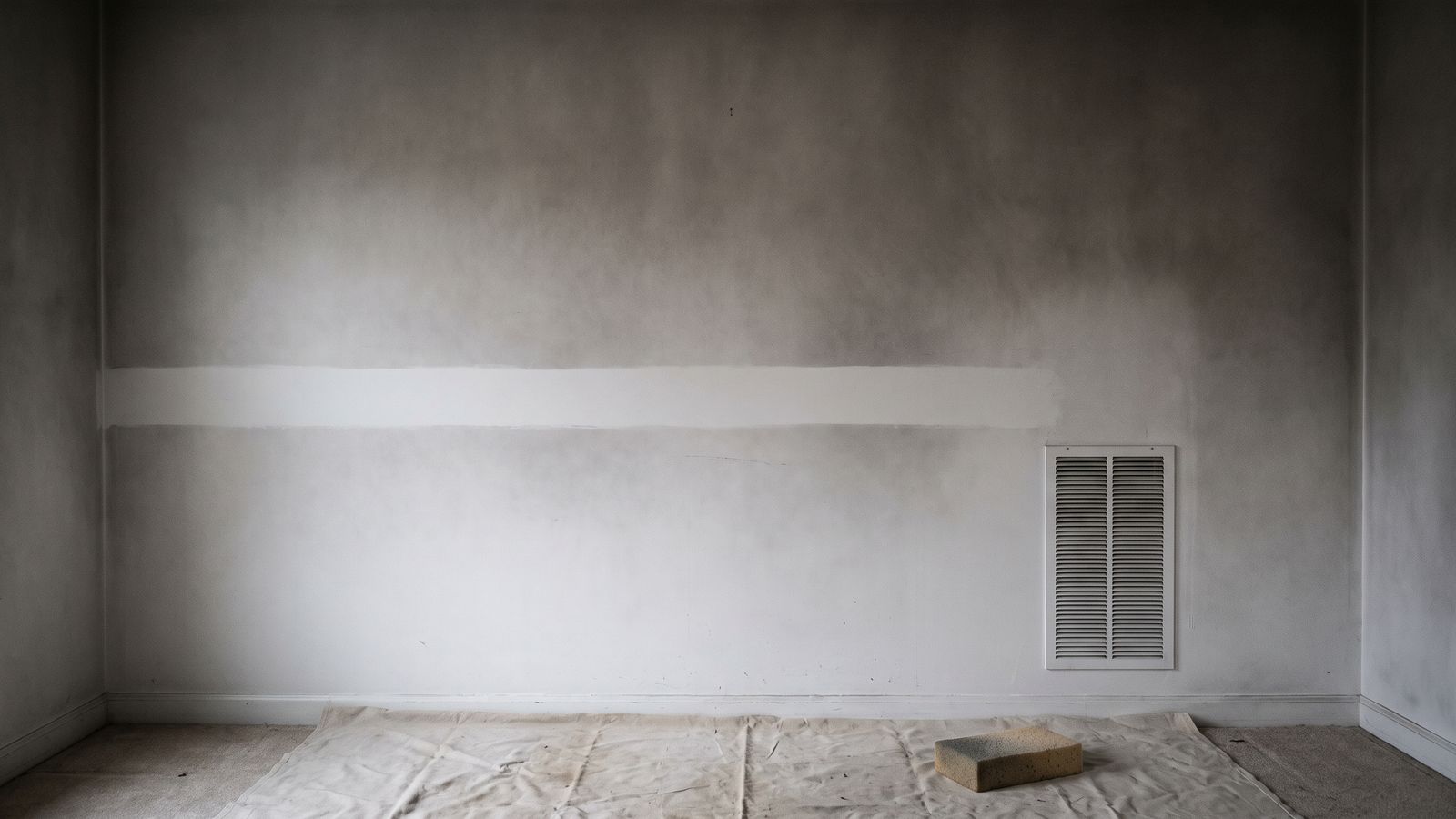 One clean stripe wiped through gray smoke damage film on a white wall beside a plain return air grille.