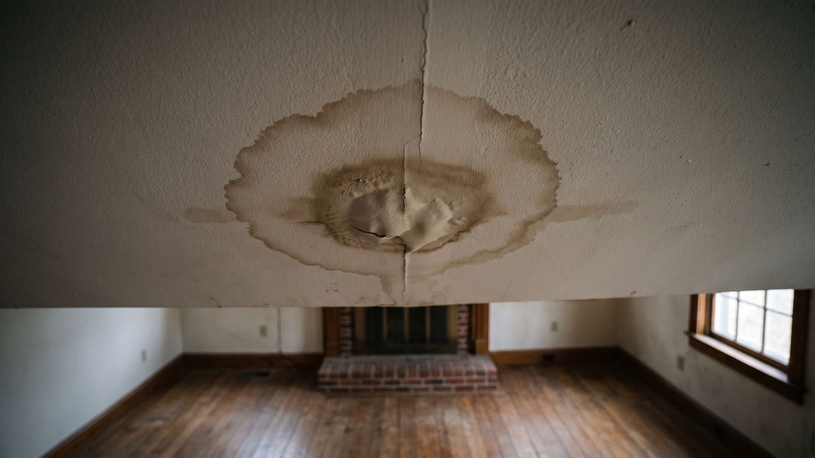 Stained ceiling below a laundry overflow Brown stain ring and sagging blistered paint on the ceiling below a laundry after washing machine overflow water damage