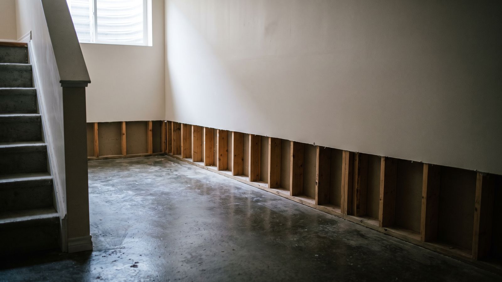 Flood-cut basement wall above a damp slab Flood-cut basement wall and bare studs over a damp slab at the demolition stage of a water damage restoration timeline