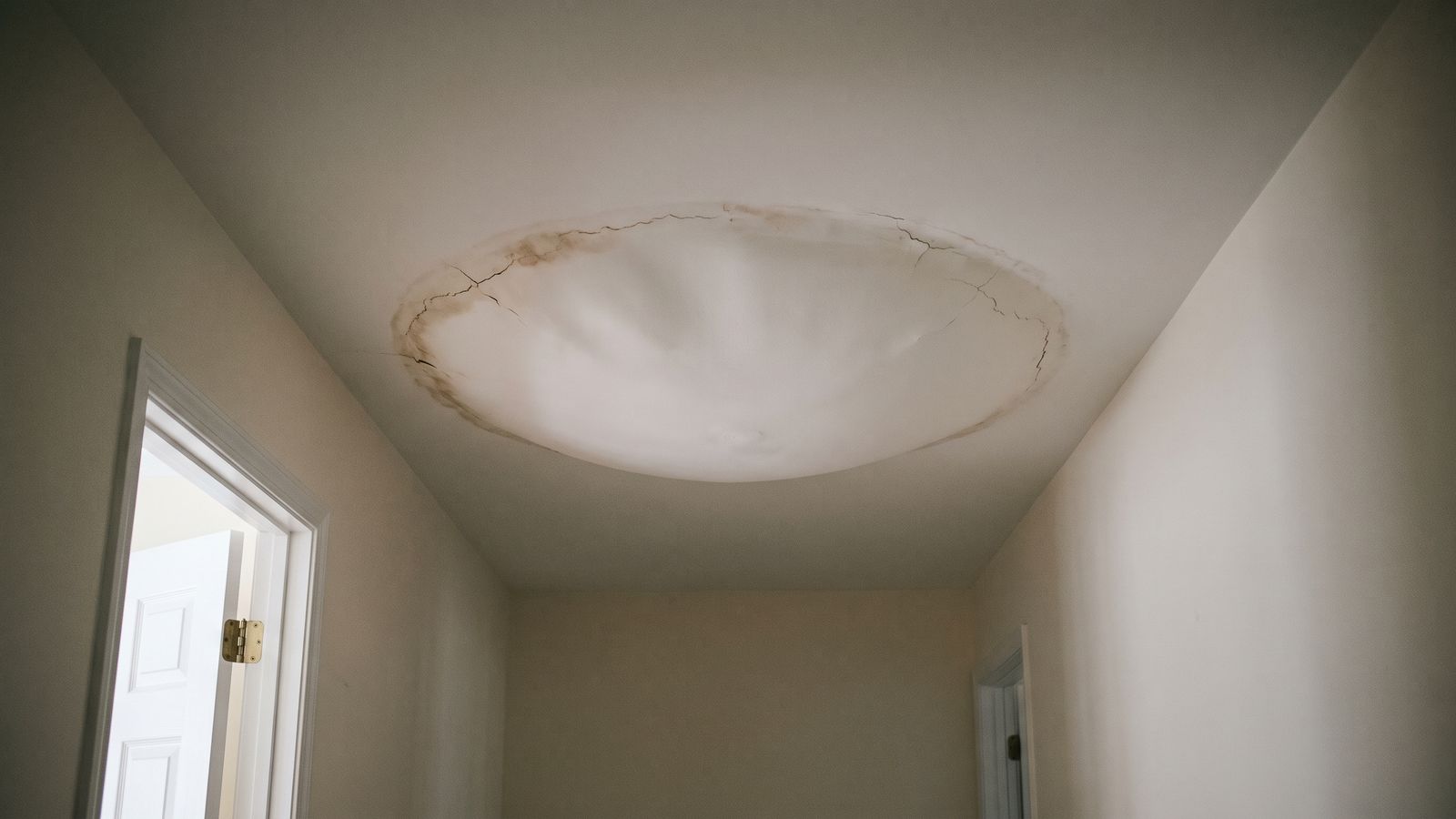 Bulging hallway ceiling holding trapped water Bulging hallway ceiling dome ringed with brown staining and fine cracks, a water damaged ceiling collapse risk
