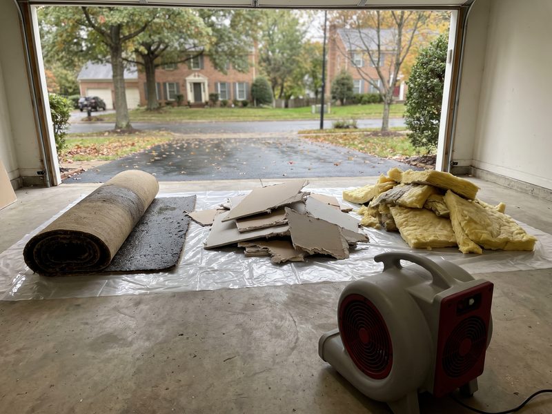 Removed carpet pad, cut drywall and wet insulation sorted into separate piles on plastic sheeting in a garage.