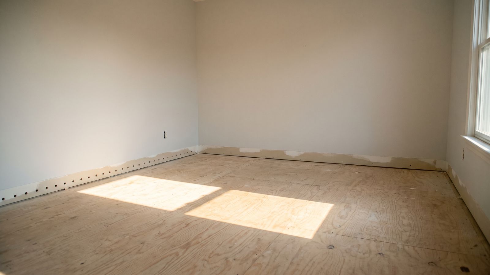 Weep holes drilled along the bottom of the drywall in an emptied room dried out after water leak damage