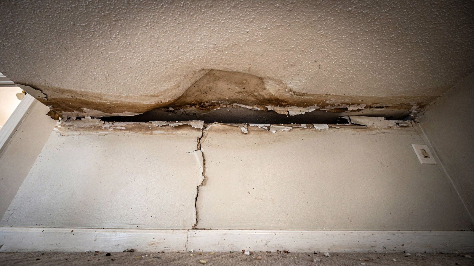 Stained Sagging Ceiling Split Open at the Wall Seam Brown-stained textured ceiling sagging and split open along the wall seam: water leak from upstairs neighbor ceiling