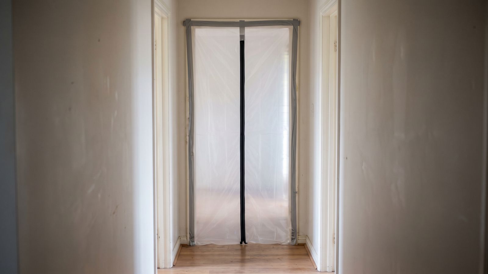 Zippered Plastic Containment Sealed Across a Doorway Doorway sealed floor to ceiling in taped plastic sheeting with a zip entry: water leak from upstairs neighbor ceiling