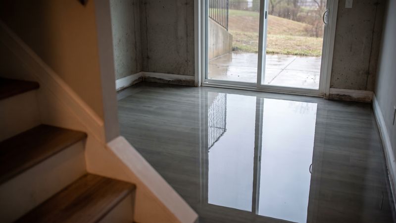 Standing water across a walk-out basement floor, the scene that sets what to do after water damage