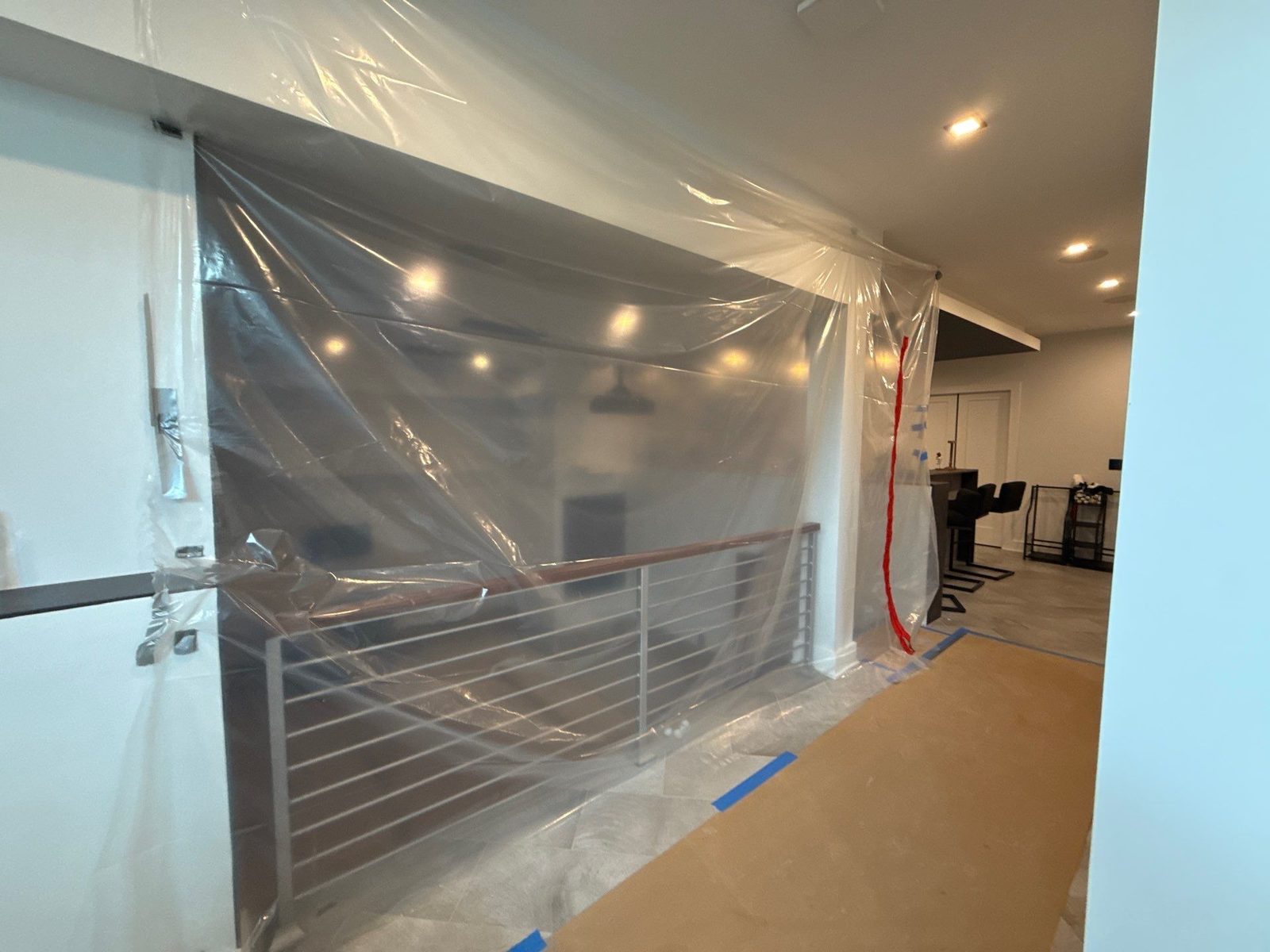 Plastic containment barrier sealing a stairwell opening and railing in an Arlington, VA home before mold work
