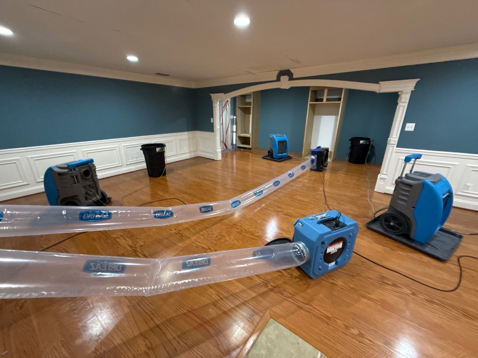 Ducted blue equipment units and dehumidifiers on an oak plank floor in a Manassas, VA house, April 2026