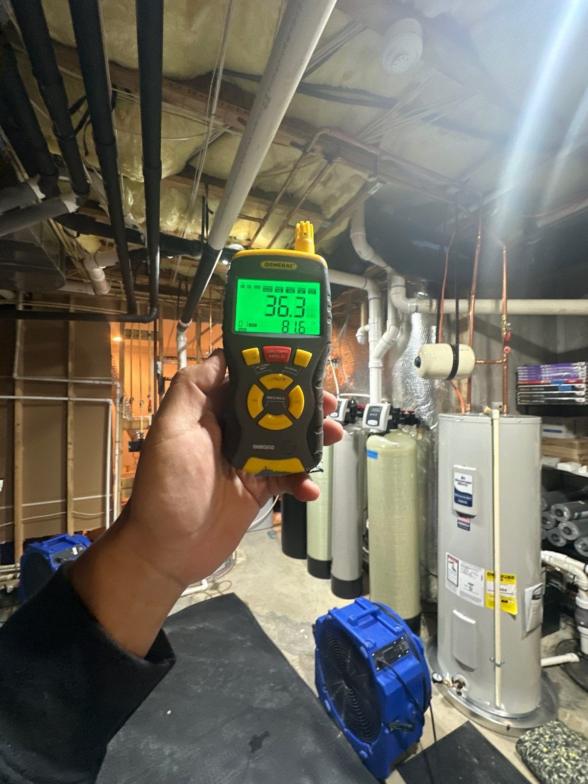 Handheld meter reading 36.3 percent relative humidity in a basement mechanical room with an air mover on the floor, McLean, VA, October 26, 2025