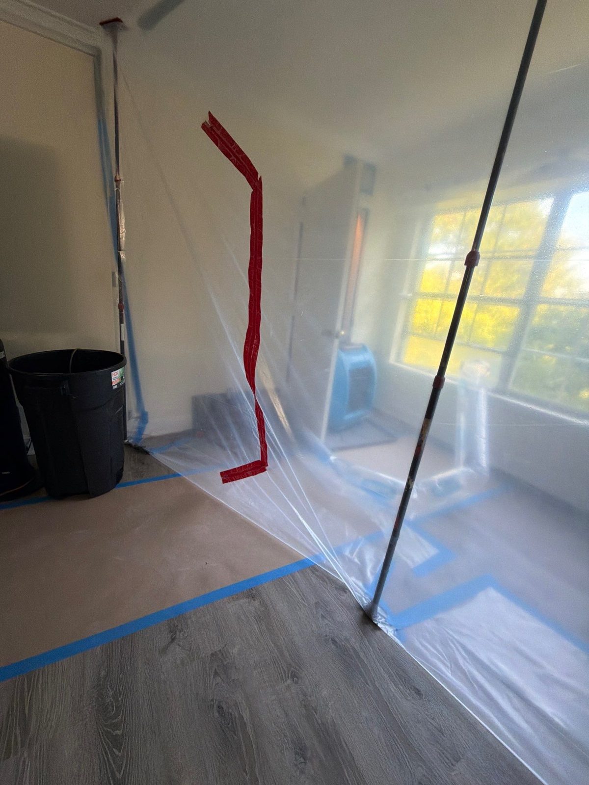 Zip-wall plastic containment with red tape and blue floor protection around a dehumidifier in a room, McLean, VA, September 2026