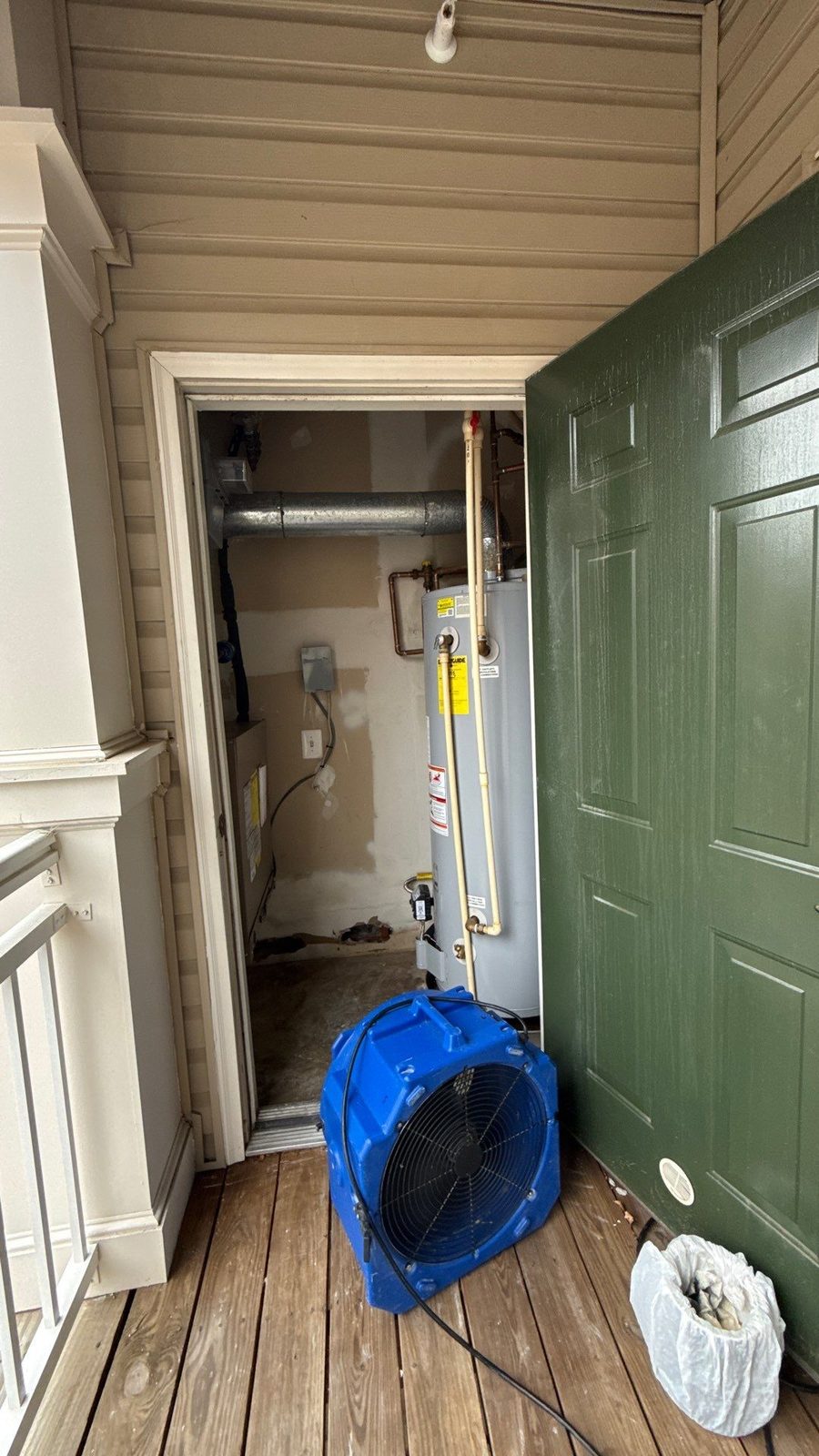 Air mover on a covered balcony outside the open door of a closet that holds a water heater, Alexandria, VA, November 2025