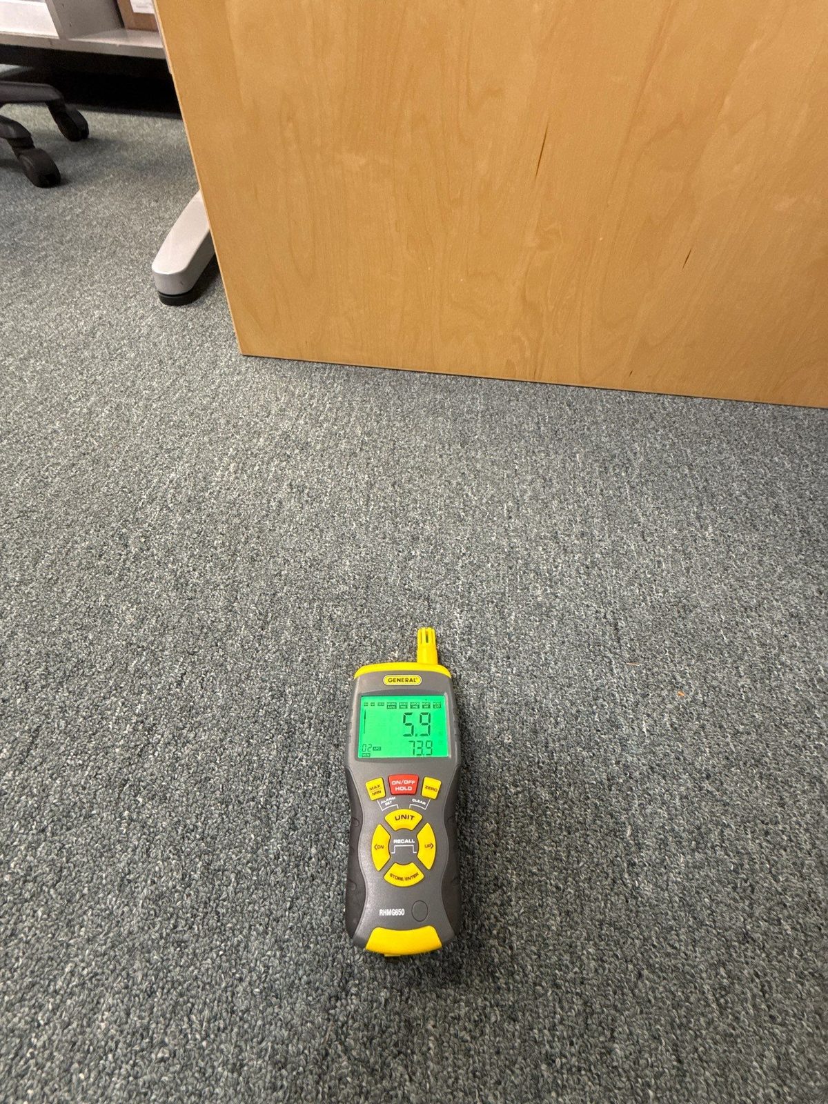Moisture meter lying on carpet beside a wooden desk, reading 5.9, Sterling, VA, September 19, 2025