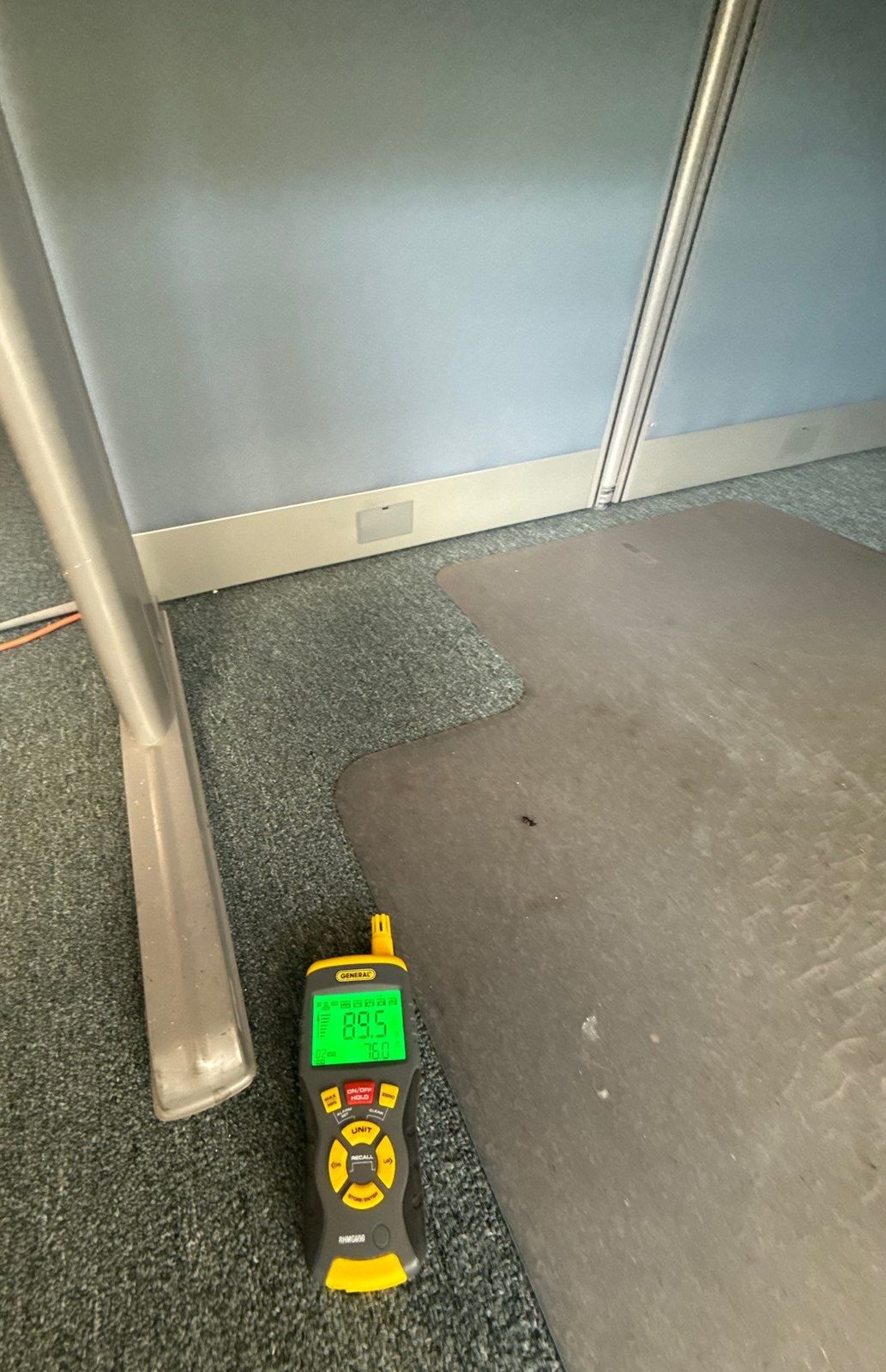 Moisture meter lying on carpet beside a floor mat and a cubicle partition, reading 89.5, Sterling, VA, September 20, 2025