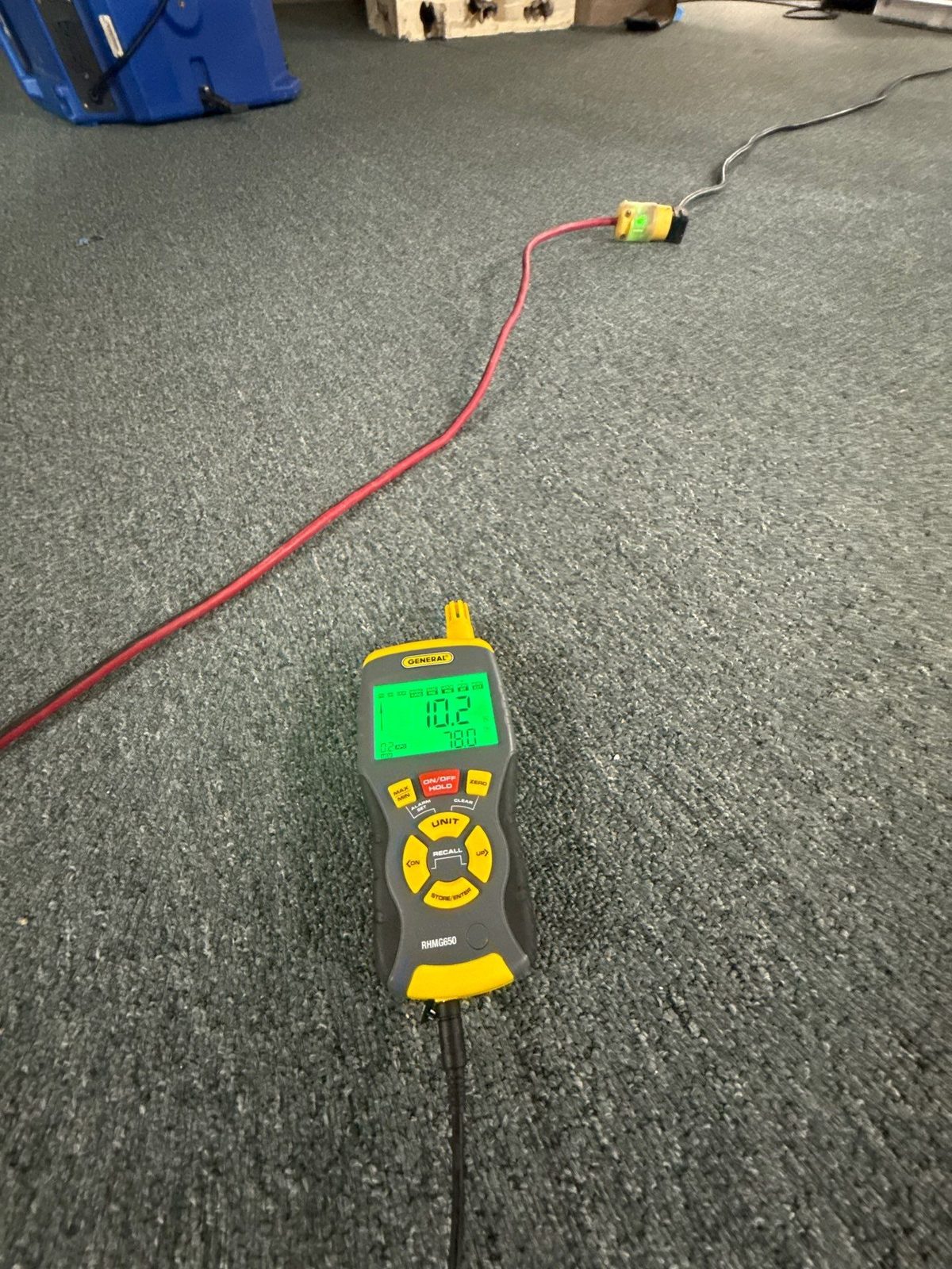 Moisture meter lying on carpet with a red extension cord and a blue air mover behind it, reading 10.2, Sterling, VA, September 23, 2025
